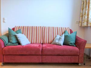 Un sofá rojo con almohadas azules y blancas. en Apartment Freiheit-La by Interhome, en Schnann
