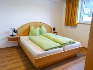 1 dormitorio con cama de madera y almohadas verdes en Apartment Freiheit-La by Interhome, en Schnann