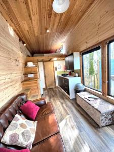 a living room with a leather couch and a kitchen at Tiny House-Hot Tub-St Clears-Pembrokeshire-Tenby in Carmarthen
