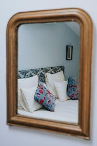 een spiegel die een bed reflecteert met kussens erop bij Le Gite de Tassigny in Meursault