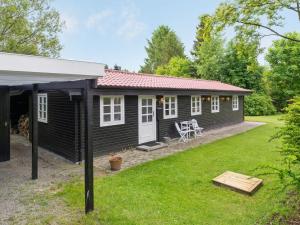 una pequeña casa negra con un patio en Holiday Home Ilena - 16-3km from the sea in Sealand by Interhome, en Borup