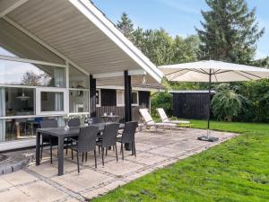 a patio with a table and chairs and an umbrella at Holiday Home Eivor - 500m from the sea in Sealand by Interhome in Hornbæk