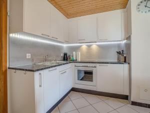 cocina con armarios blancos y encimera en Apartment Chalet Niderärne by Interhome en Lax