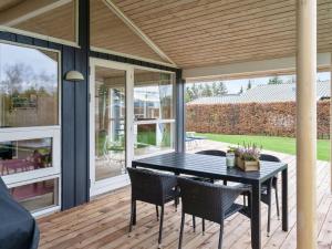 a screened porch with a black table and chairs at Holiday Home Rixa - 525m from the sea in Sealand by Interhome in Slagelse