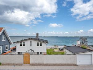 a white house with the ocean in the background at Holiday Home Elsabeth - 20m from the sea in Sealand by Interhome in Helsingør