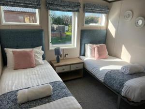 two beds in a room with two windows at Darwin Lodge with Hot Tub in Malton