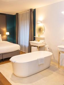 een badkamer met een bad, een wastafel en een bed bij Ezia in Montlivault