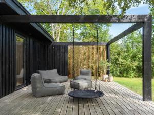 una terrazza in legno con 2 sedie e un'altalena di Holiday Home Hævnir - 1km from the sea in Sealand by Interhome a Vejby
