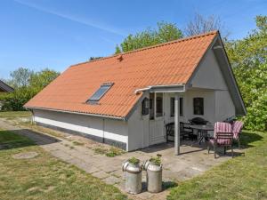 ein kleines Haus mit einem orangenen Dach und einem Tisch in der Unterkunft Holiday Home Marita - 225m from the sea in Sealand by Interhome in Korsør