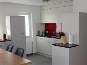 una cocina con armarios blancos y una mesa con sillas. en Apartment Pardi 3 Simeon by Interhome, en Lenz