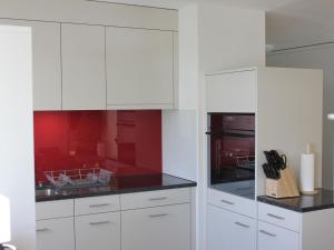 cocina blanca con paredes rojas y armarios blancos en Apartment Pardi 3 Simeon by Interhome, en Lenz