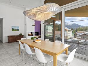 une salle à manger avec une table en bois et des chaises blanches dans l'établissement Apartment Parvenda by Interhome, à Lenzerheide