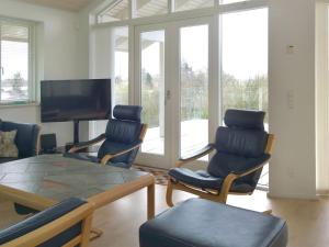 een woonkamer met een tafel en stoelen en een televisie bij Holiday Home Vicente - 130m from the sea in Sealand by Interhome in Jægerspris