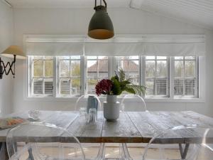 a dining room table with chairs and a vase with flowers at Holiday Home Hjort - 100m from the sea in Sealand by Interhome in Dronningmølle