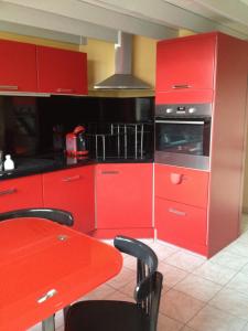 eine Küche mit roten Schränken und einem Tisch mit Stühlen in der Unterkunft appartement 30m2 calme proche du centre ville in Lunel