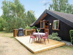 een terras met een tafel en stoelen voor een cabine bij Holiday Home Ija - 200m from the sea in Sealand by Interhome in Føllenslev