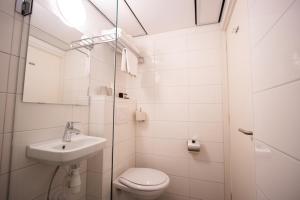 a white bathroom with a sink and a toilet at Hotel De Boei in Egmond aan Zee