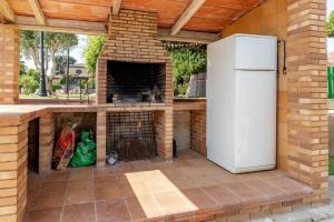 an outdoor kitchen with a brick fireplace and a refrigerator at Casa rural con piscina, barbacoa, WIFI in Vilobí d'Onyar