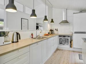 eine weiße Küche mit weißen Schränken und Holzböden in der Unterkunft Holiday Home Liselotte - 200m from the sea in Sealand by Interhome in Rørvig