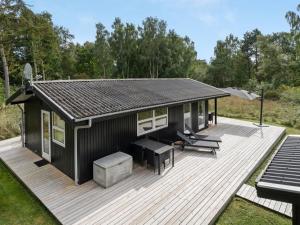 eine schwarze Hütte mit einem Picknicktisch auf dem Deck in der Unterkunft Holiday Home Liselotte - 200m from the sea in Sealand by Interhome in Rørvig