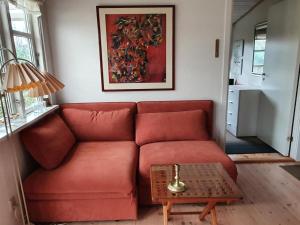 uma sala de estar com um sofá vermelho e uma mesa em Holiday Home Haldis - 120m from the sea in Lolland- Falster and Mon by Interhome em Stubbekøbing