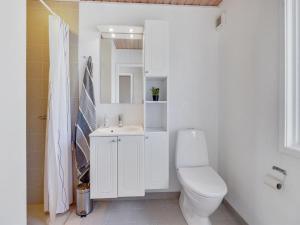 een witte badkamer met een toilet en een wastafel bij Holiday Home Rico - 200m from the sea in Sealand by Interhome in Vordingborg