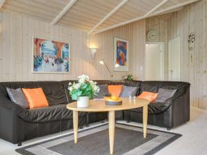 ein Wohnzimmer mit einem schwarzen Ledersofa und einem Tisch in der Unterkunft Holiday Home Sophi - all inclusive - 425m from the sea by Interhome in Fårevejle