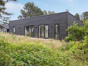 ein schwarzes Haus auf einem Hügel mit Bäumen in der Unterkunft Holiday Home Gjorgje - 100m from the sea in Sealand by Interhome in Tjørneholm