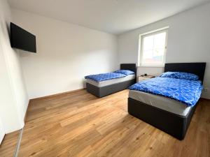 two beds in a room with wood floors at Wochenzimmer - Premium Apartments für Monteure, Event- und Projektteams in Sankt Peter-Freienstein