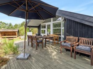 a wooden deck with a table and chairs and an umbrella at Holiday Home Lisbeth - 400m from the sea by Interhome in Yderby
