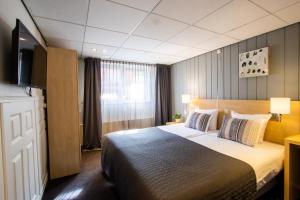 ein Hotelzimmer mit einem Bett und einem Flachbild-TV in der Unterkunft Hotel De Boei in Egmond aan Zee