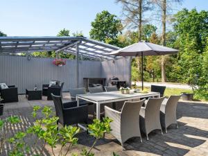 une terrasse avec une table, des chaises et un parasol dans l'établissement Holiday Home Tannie - 300m from the sea in Sealand by Interhome, à Strøby