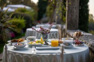 a white table with breakfast foods and orange juice at Hotel Villa Cipriani in Asolo