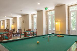 a pool table in a room with tables and chairs at Hotel Braga Falperra in Braga