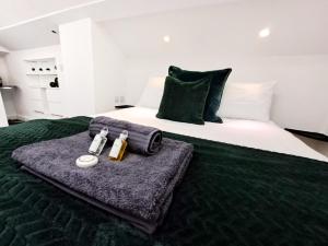 SPACIOUS 3 Bed APARTMENT WITH EN-SUITES في واتفورد: سرير مع بطانيه خضراء وزجاجتين من العطور
