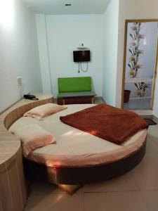 a bedroom with a large bed with a green seat at Hotel Aashiyana & Restaurant, Chittorgarh in Chittaurgarh