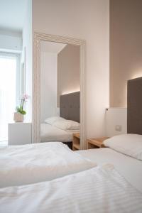 een slaapkamer met 2 bedden en een spiegel bij Hotel Rolly in Riva del Garda