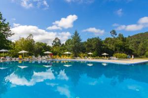 una gran piscina con sillas y sombrillas en Hotel Braga Falperra, en Braga