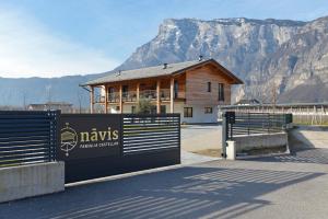 a building with a fence in front of a mountain at Bed and Breakfast NAVIS in Nave San Rocco