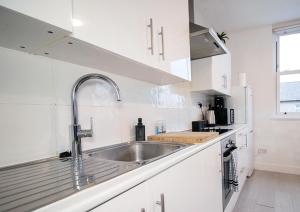 cocina blanca con fregadero y fregadero en SPACIOUS 3 Bed APARTMENT WITH EN-SUITES, en Watford