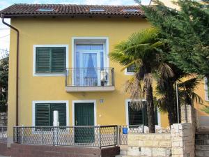 una casa amarilla con un balcón y una palmera en Holiday House Sara, en Opatija