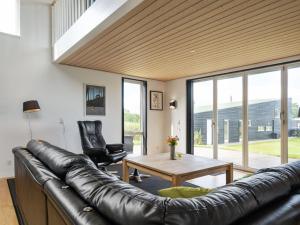 een woonkamer met een leren bank en een tafel bij Holiday Home Lyly - 100m from the sea in Funen by Interhome in Asperup