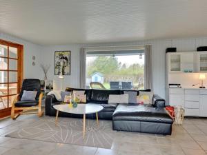 a living room with a black leather couch and a table at Holiday Home Alrich - 500m from the sea in Funen by Interhome in Svendborg