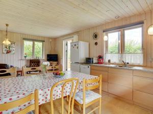 y cocina con mesa, sillas y nevera. en Holiday Home Rəzvan - 120m from the sea in Funen by Interhome, en Vedelshave