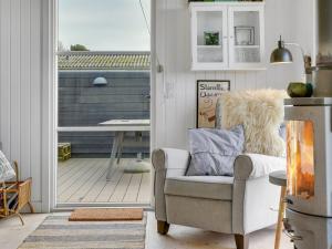 ein Wohnzimmer mit einem Stuhl und einem Balkon in der Unterkunft Holiday Home Akseline - 20m from the sea in Funen by Interhome in Assens