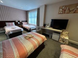 a hotel room with two beds and a flat screen tv at Acer Lodge Guest House in Edinburgh