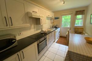 a kitchen with white cabinets and a black counter top at Falcon Lodge in Aviemore