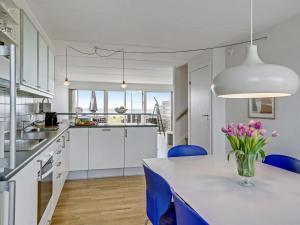 een witte keuken met een tafel en blauwe stoelen bij Apartment Ninne - 50m from the sea in Funen by Interhome in Assens
