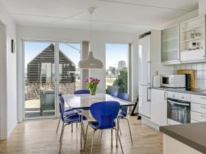 een keuken en eetkamer met een tafel en blauwe stoelen bij Apartment Ninne - 50m from the sea in Funen by Interhome in Assens