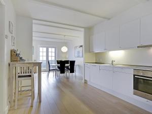 a kitchen with white cabinets and a table with chairs at Apartment Terina - 5m from the sea in Funen by Interhome in Bagenkop